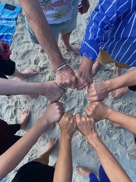 A forum retreat closing circle, hands joined in trust